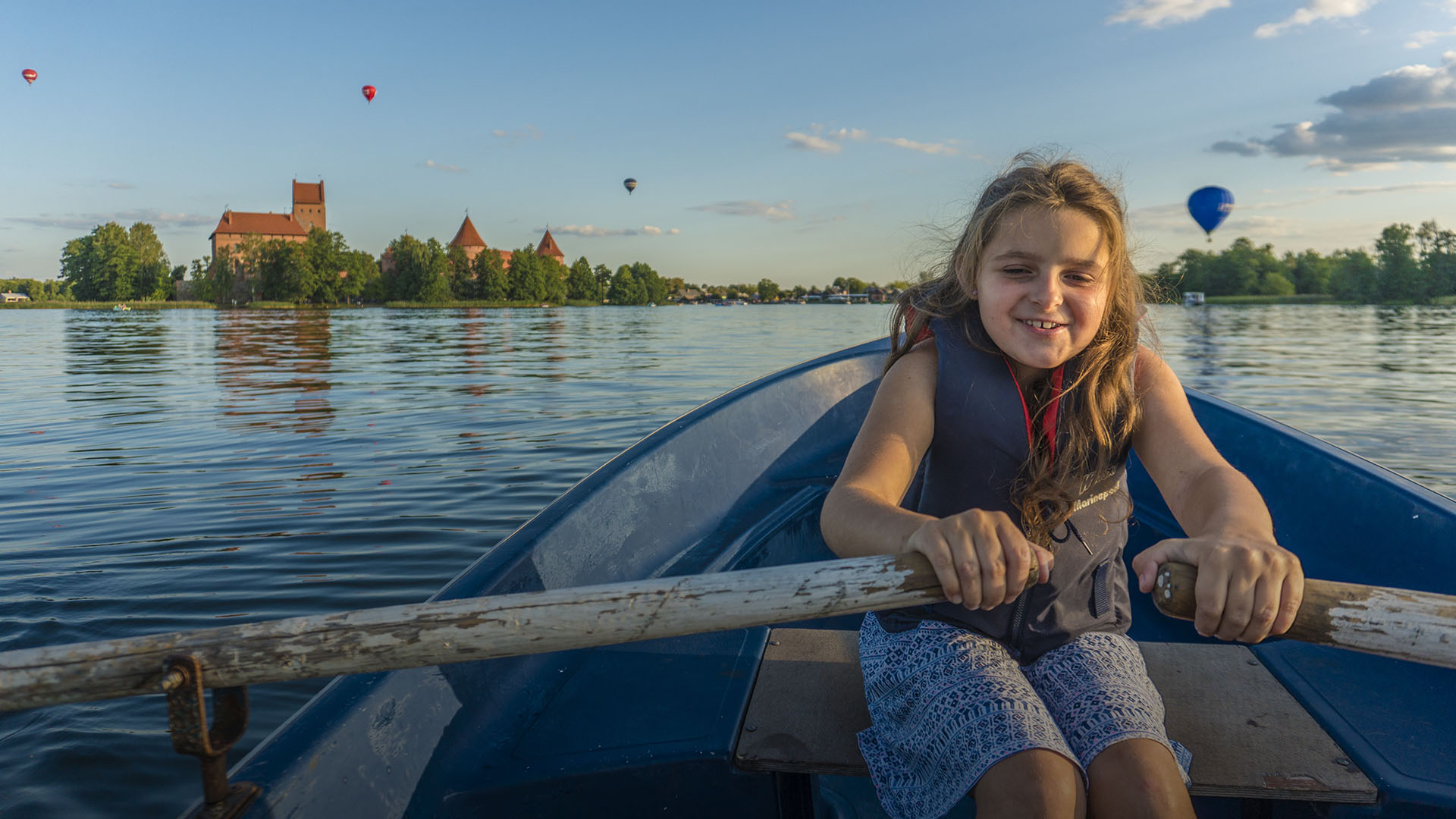 Little girl smiling and rowing a boat