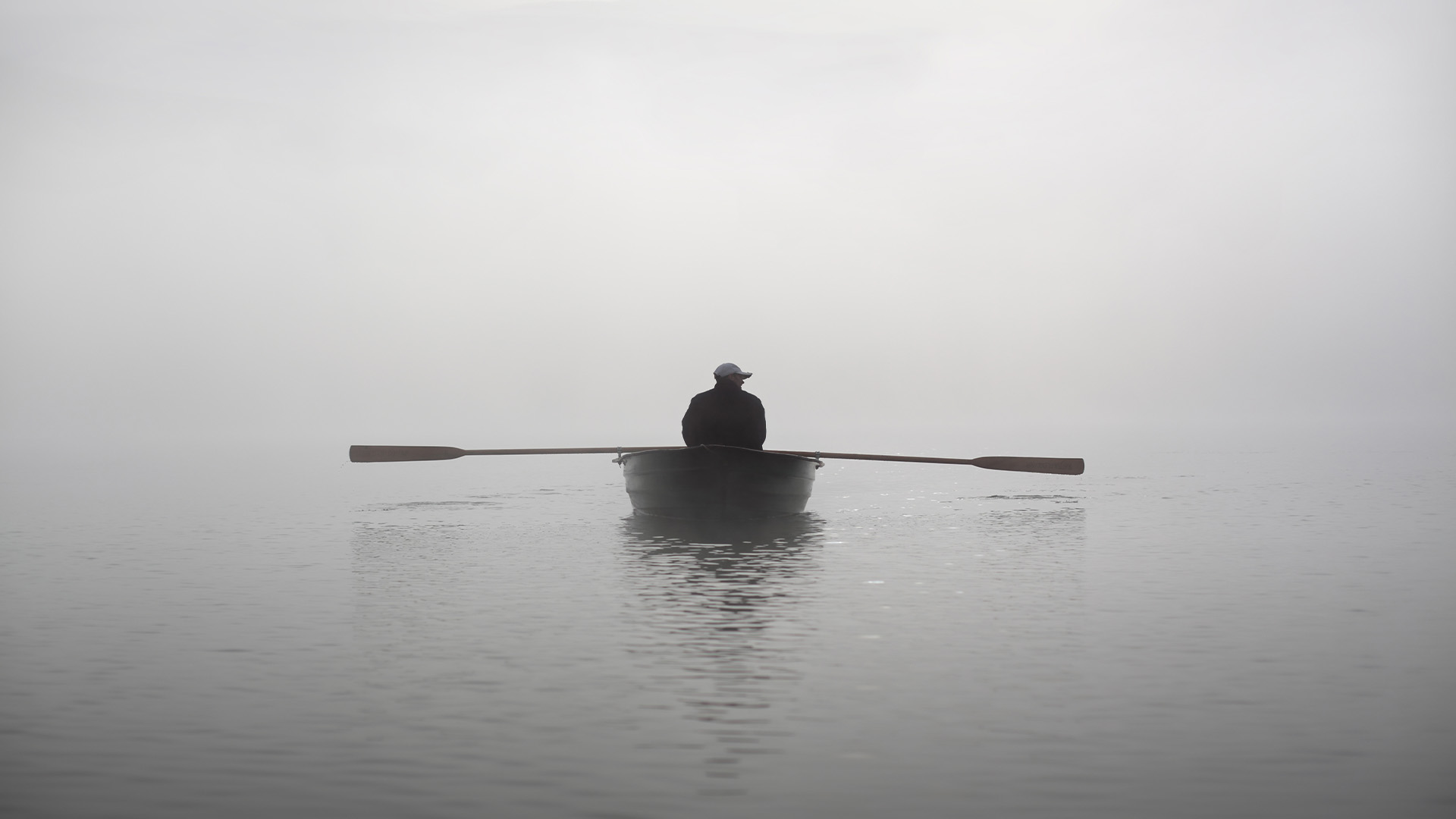 Man rowing on foggy water