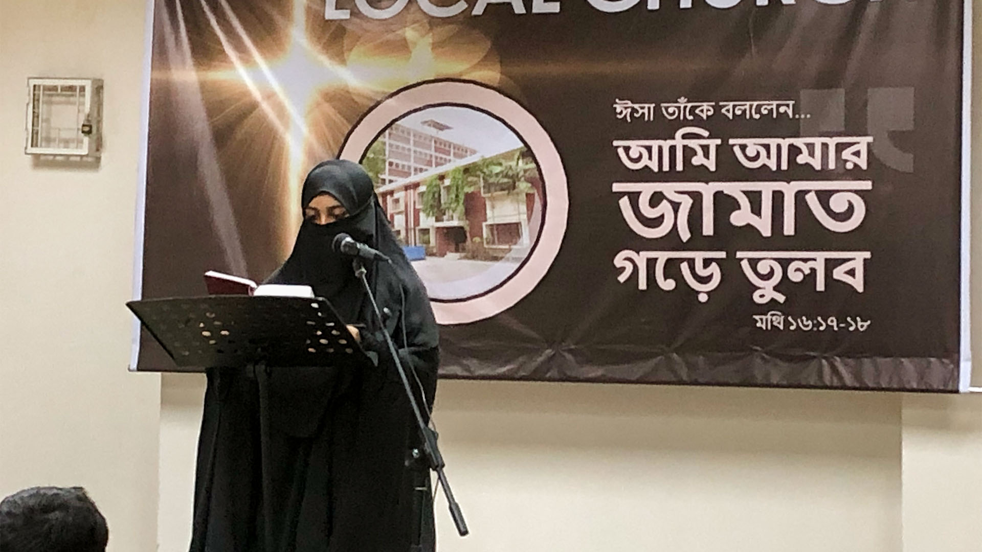 A woman in a hijab reads scripture at the front of her church