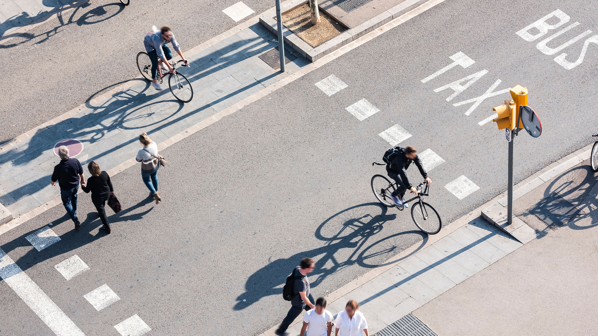 A busy crosswalk with people walking and riding bicycles 