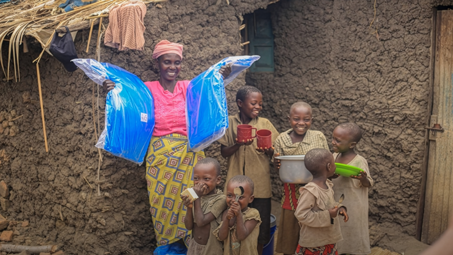 Woman stands with food in front of her house