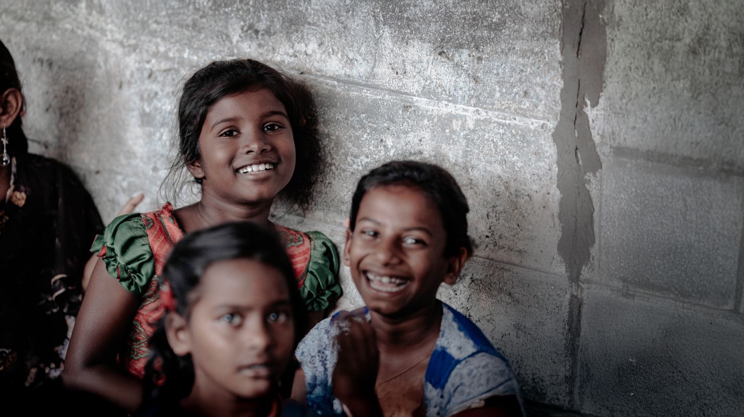 Indian orphans smiling against concrete block wall