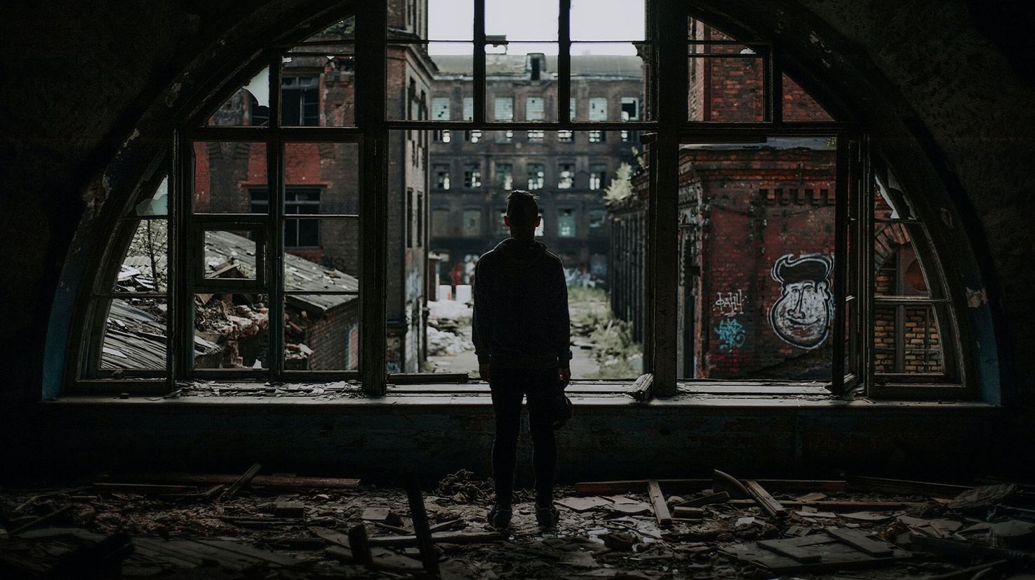 man standing by broken window