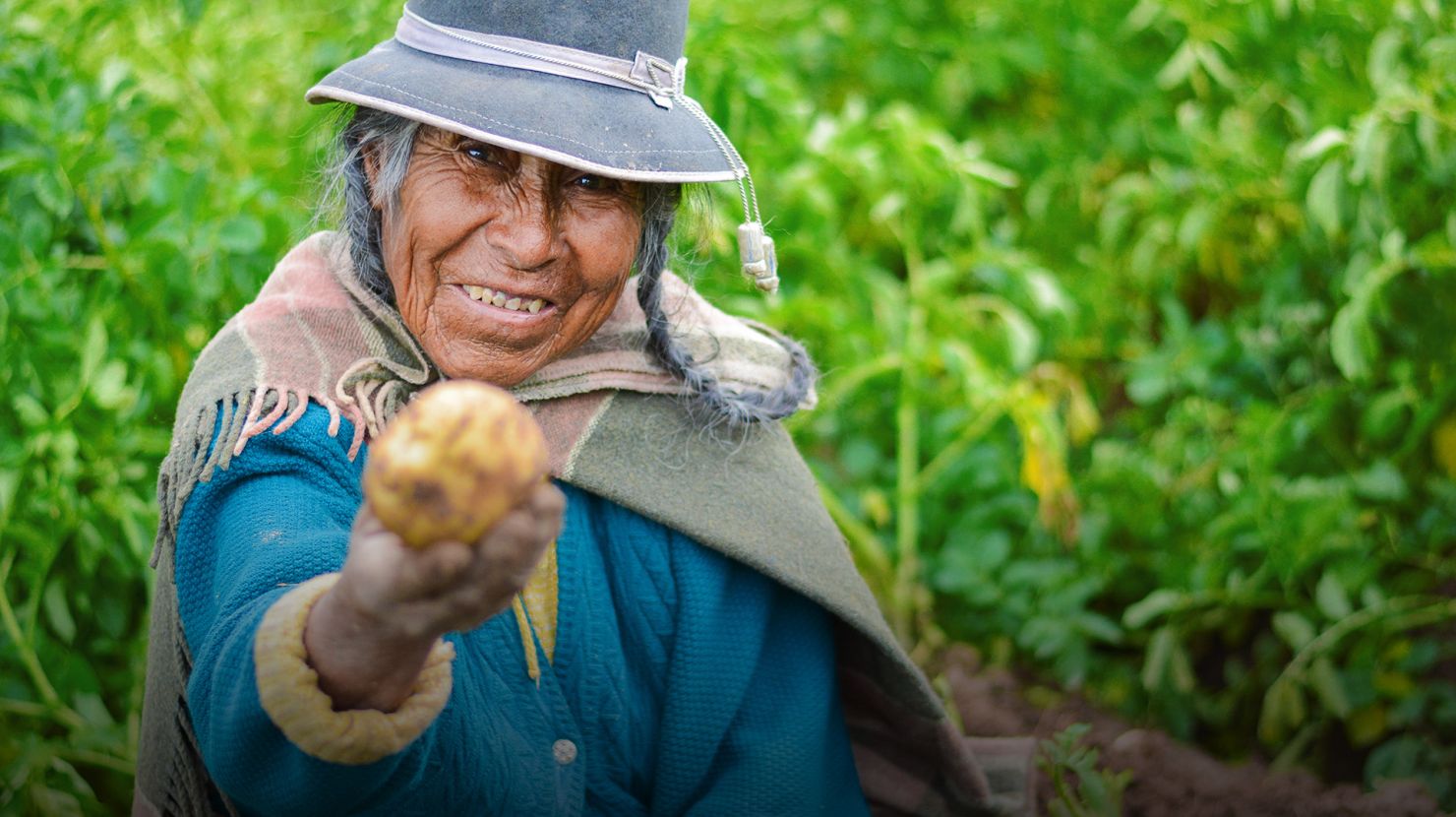 Woman smiling happily offering the viewer a potato