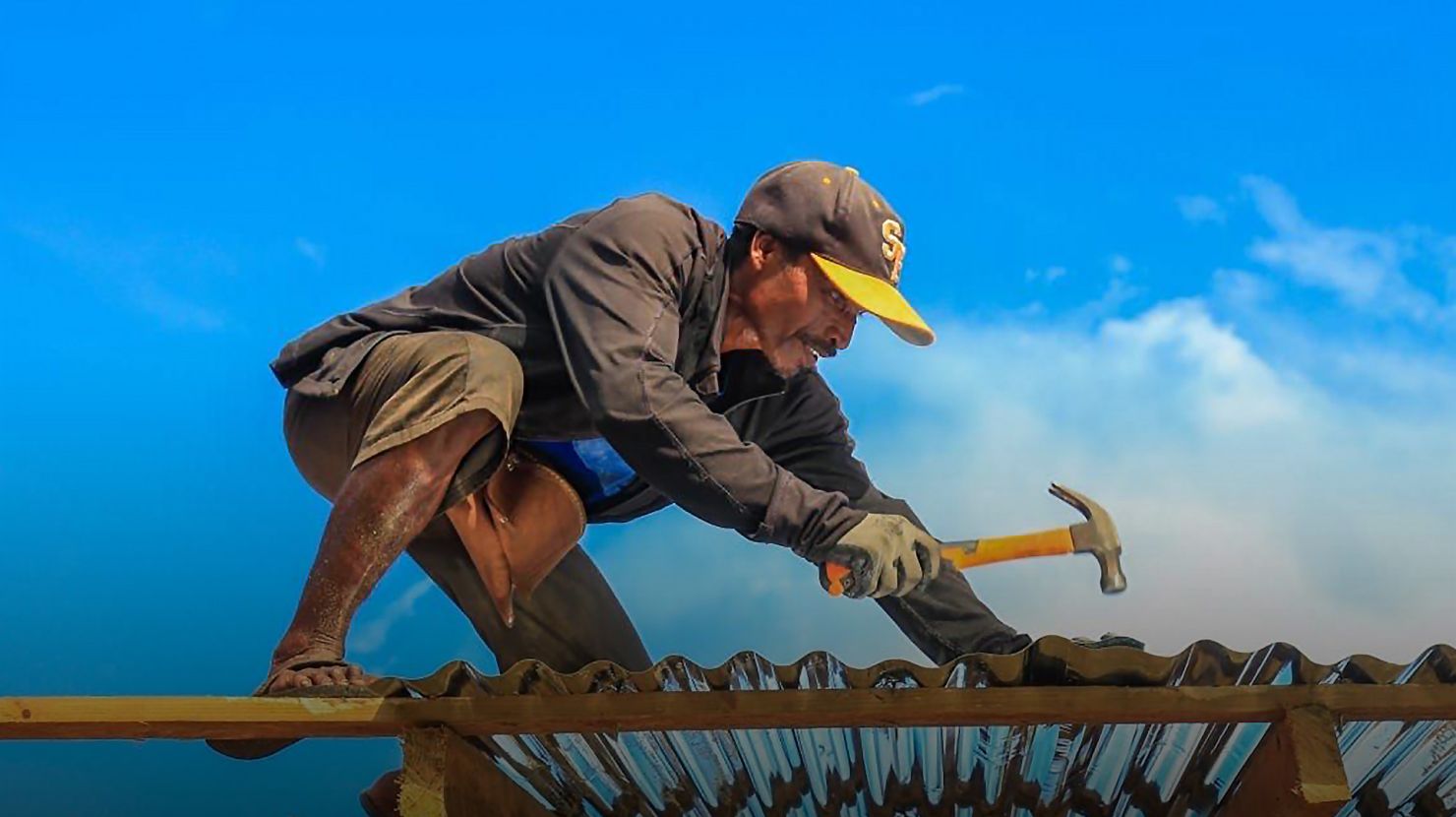 man hammering in a tin roof