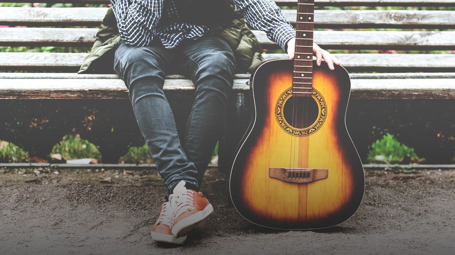boy sitting down holding guitar