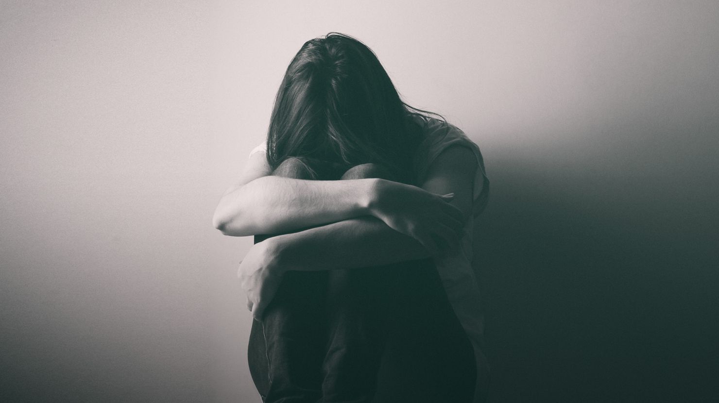 Teenager girl sitting alone on the floor in a dark room