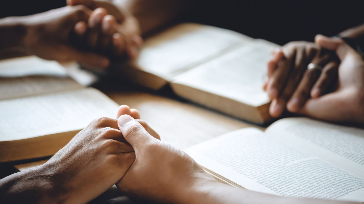 Holding hands in prayer on Bibles