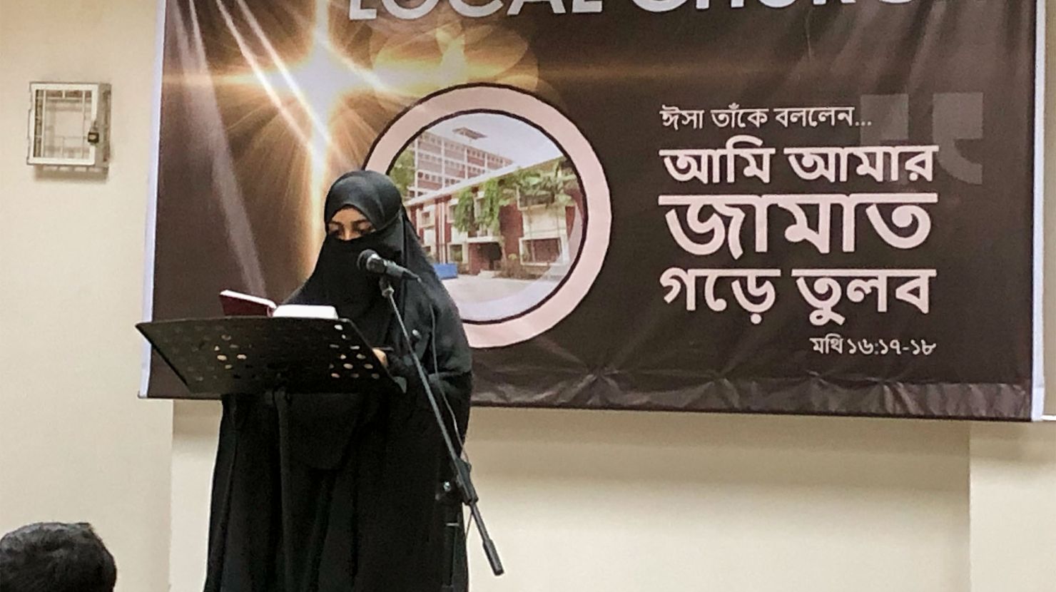 A woman in a hijab reads scripture at the front of her church