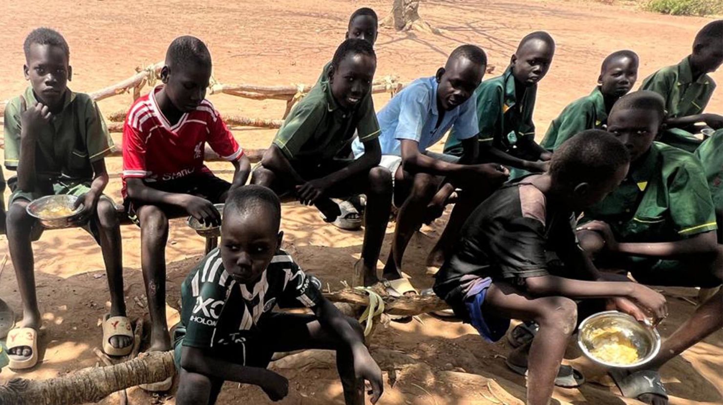 A group of boys enrolled in the children’s care program enjoys a meal before class begins.