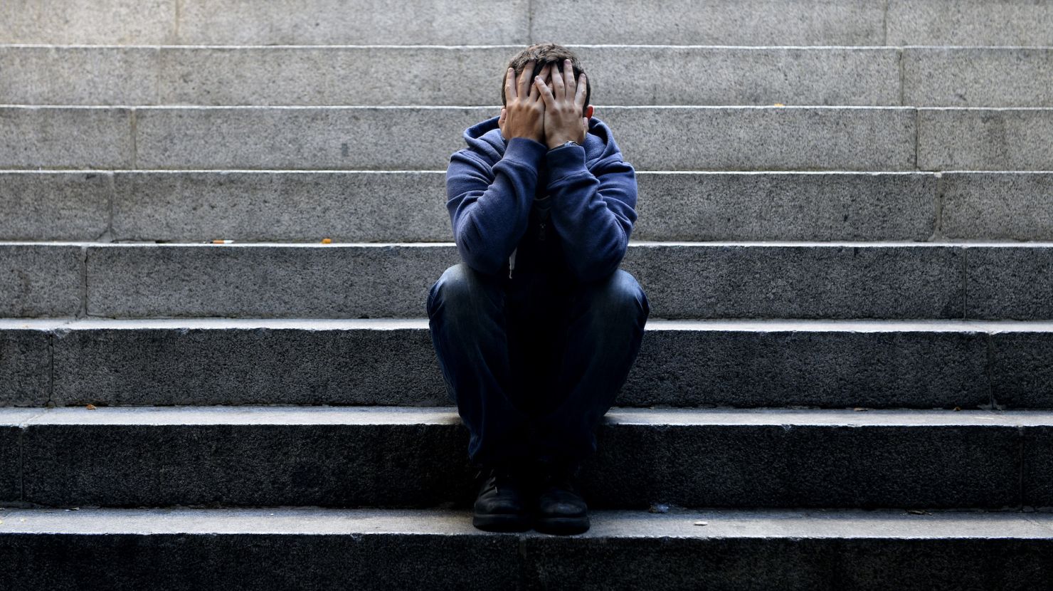 Man sitting on steps with face in his hands