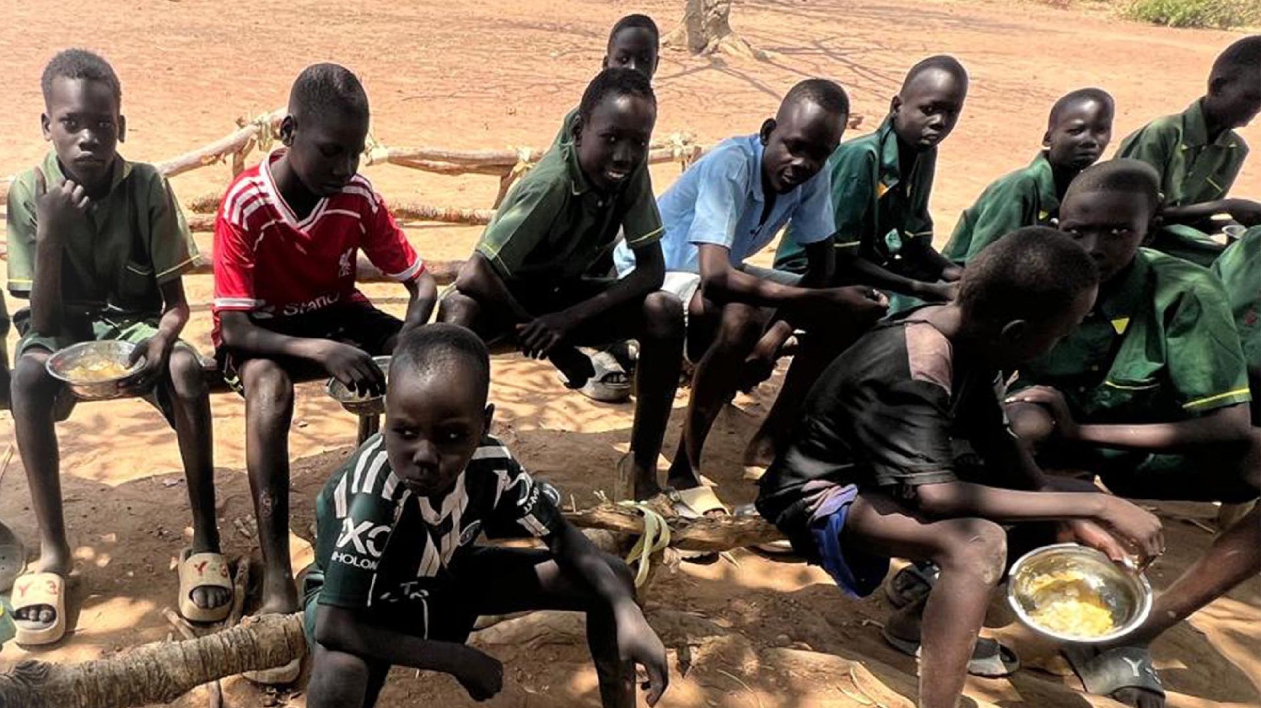 A group of boys enrolled in the children's care program enjoys a meal before class begins.